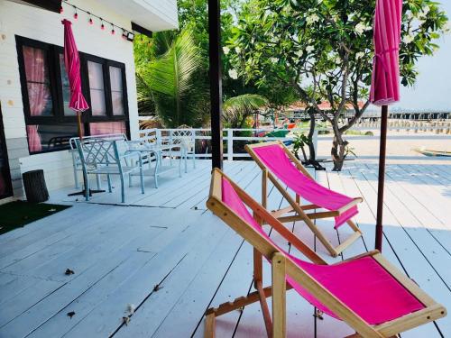 two pink chairs and an umbrella on a deck at Karoon Sea View Lodge in Hua Hin