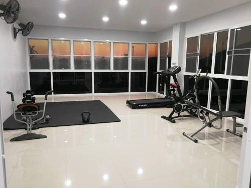 a gym with two treadmills and two exercise bikes at ศุภักษรอพาร์ทเม้นและสระว่ายน้ำ Supakson apartement and pools in Sawankhalok