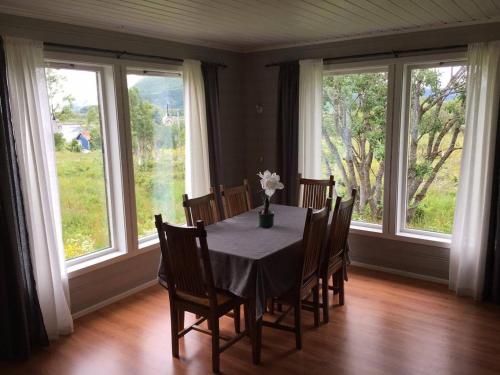 a dining room with a table and chairs and windows at Holiday Home Lofoten in Lyngværet