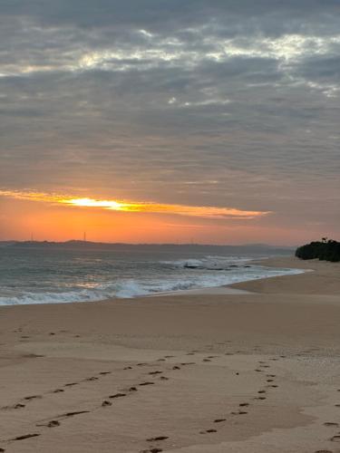 a footprints in the sand on a beach at sunset at BAYU COVE Private Villa in Tangalle