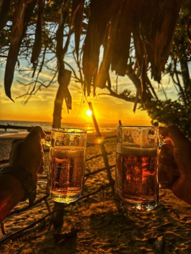 two glasses of beer sitting on a table at the beach at BAYU COVE Private Villa in Tangalle