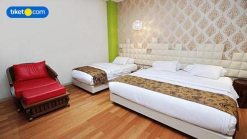 a hotel room with two beds and a red chair at Griya Jogja Hotel in Yogyakarta