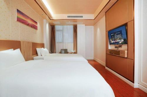 a hotel room with two beds and a flat screen tv at Quanzhou Binhai Hotel in Quanzhou