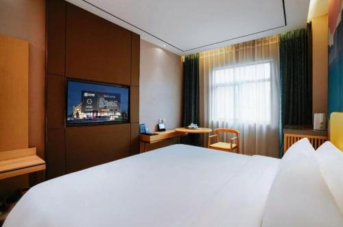 a hotel room with a large bed and a television at Quanzhou Binhai Hotel in Quanzhou