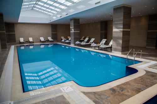 une grande piscine dans un hôtel avec des chaises et des tables dans l'établissement The Baron Hotel - Karbala, à Karbala