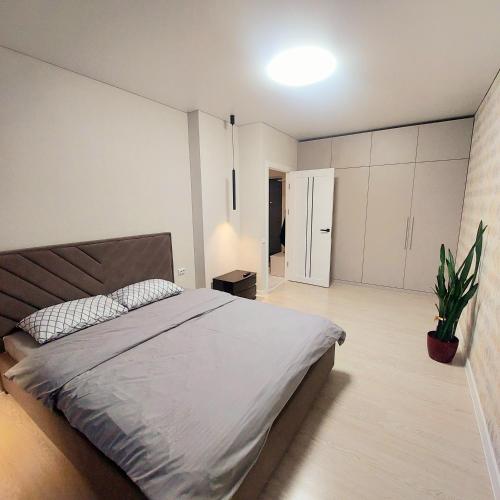 a bedroom with a large bed and a potted plant at Однокімнатна квартира в ЖК Над бугом in Khmelʼnytsʼkyy