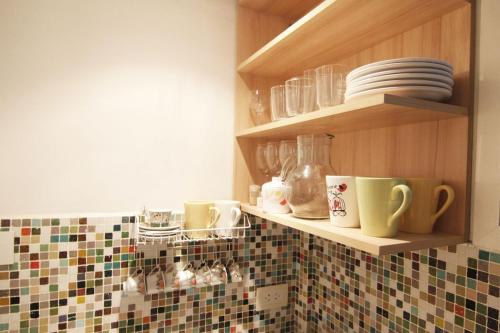 una cocina con tazas y platos en una pared de azulejos en Alex Apartment en Buenos Aires
