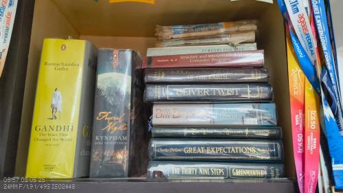 a stack of books sitting on a shelf at The Mangosteen Homestay in Kodanad