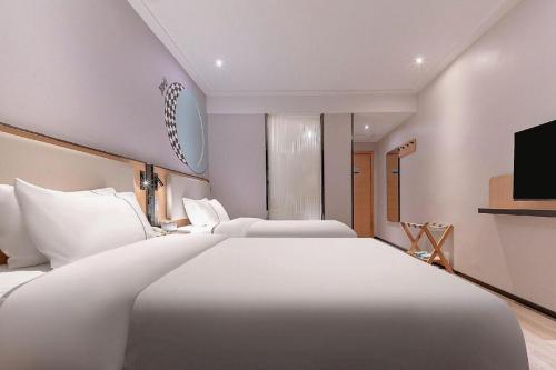 a hotel room with two beds and a television at City Comfort Inn Liuzhou High-speed Railway Station in Liuzhou