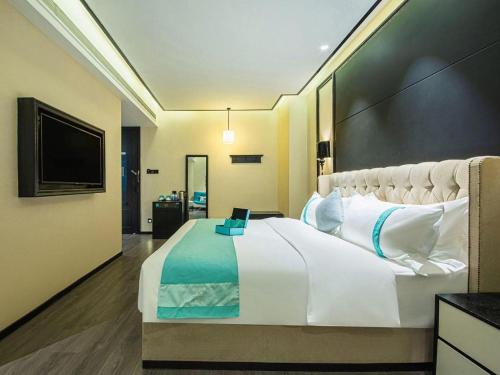 a bedroom with a large bed with a laptop on it at Xana Hotelle Nanchang Tengwang Pavilion Wanshougong in Nanchang