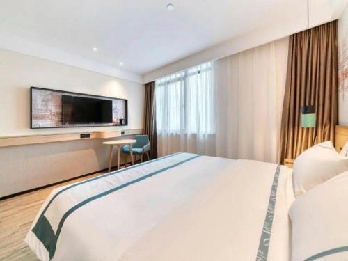 a hotel room with a large bed and a flat screen tv at City Comfort Inn Lijiang Ancient Town in Lijiang