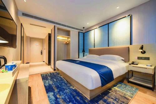 a bedroom with a large bed and a large window at Echarm Hotel Kunming High-speed Railway South Station Chunrong Street Metro Station in Kunming