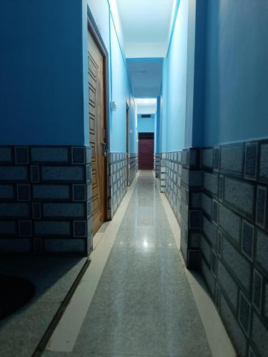 a long hallway with blue walls and a door at SRI Ganesh Hotel Fooding & Lodging in Bongaigaon