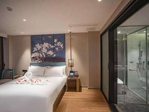 a bedroom with a large white bed with a painting on the wall at Magnotel Hotel Guangyuan Nanhe Bus Station Beijing Road in Guangyuan
