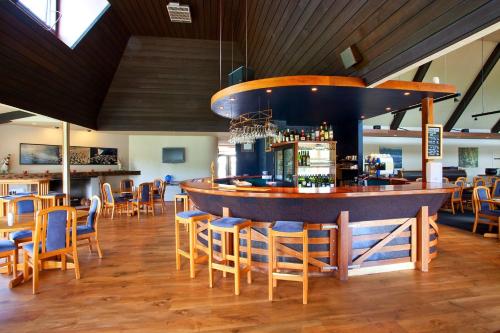 a restaurant with a bar with wooden chairs and tables at Distinction Heritage Gateway Hotel in Omarama