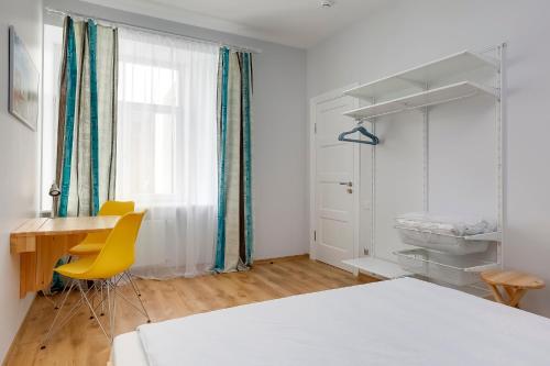 a bedroom with a desk and a table and yellow chairs at Orange Cat Rooms in Riga
