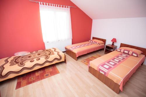 three beds in a room with red walls at Guesthouse Capistro in Bilje
