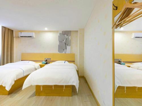 a bedroom with two beds and a mirror at GreenTree Inn Express Shanghai Baoshan District Youyi Road Metro Station in Baoshan