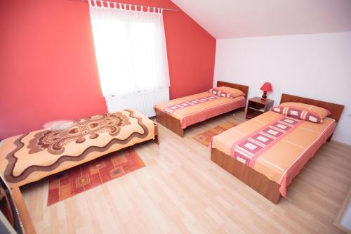 three beds in a room with red walls at Guesthouse Capistro in Bilje