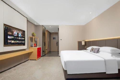 a bedroom with a white bed and a flat screen tv at E-Cheng Hotel Yangjiang Baili Plaza in Yangjiang