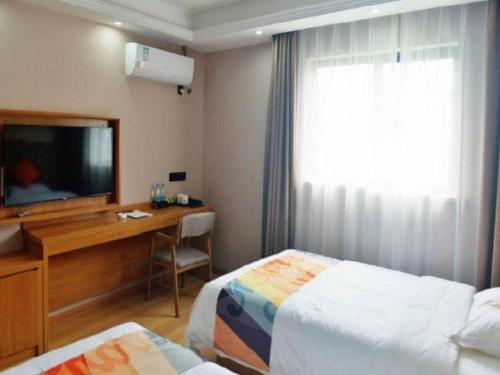 a hotel room with two beds and a desk and a television at Shell Hotel Wuhu Jiujiang District Daqiao Town Huashan Road in Wuhu