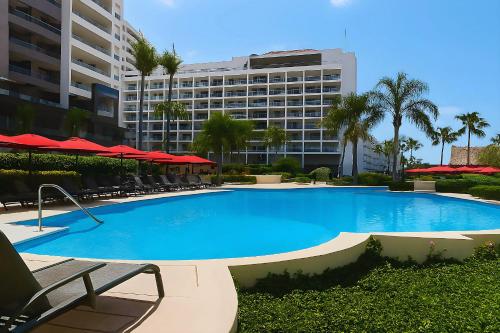 a large swimming pool with chairs and a large building at Grand Venetian Comfort in Puerto Vallarta