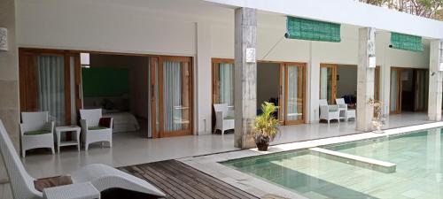 a house with a pool and chairs and a table at Villa Putih Lovina in Lovina