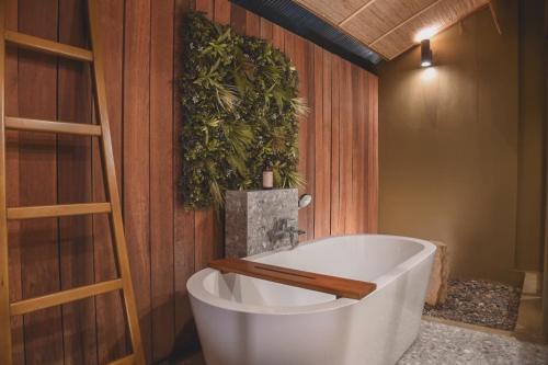 a bath tub in a bathroom with a plant on the wall at Gategaa Village in Chiang Mai