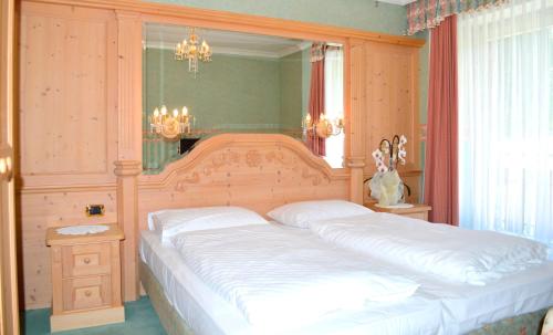 a bedroom with a large bed with a wooden headboard at Pension Panorama in San Lorenzo di Sebato