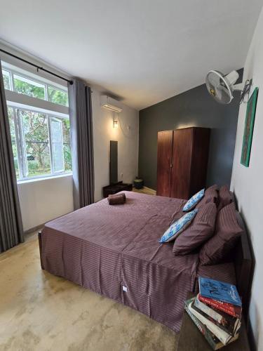 a bedroom with a bed with purple sheets and a window at The Cottage Kandy in Kandy