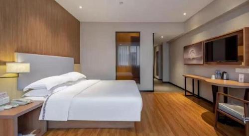 a bedroom with a large white bed and a desk at JTOUR Inn Wuhan Textile University in Wuhan