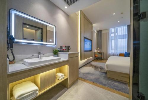 a bathroom with a sink and a bed at Borrman Hotel Zhangzhou Baolong Plaza in Zhangzhou