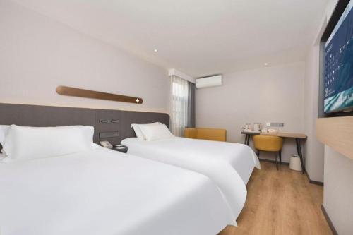 two beds in a hotel room with a tv at Jinjiang Inn Shenzhen Airport in Shenzhen