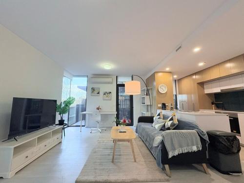 a living room with a couch and a flat screen tv at Cozy 2B apartment in Belconnen GYM POOL in Belconnen