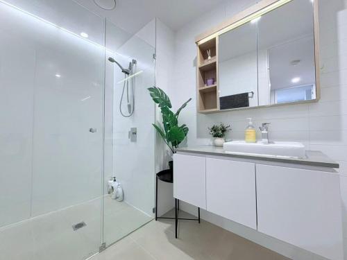 a white bathroom with a sink and a shower at Cozy 2B apartment in Belconnen GYM POOL in Belconnen