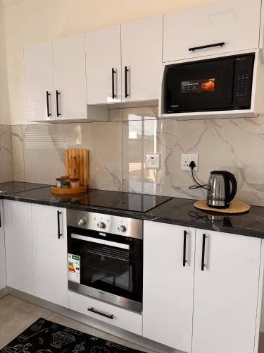 a kitchen with white cabinets and a black counter top at InWeFT Coastal Homes Apartment B in Swakopmund