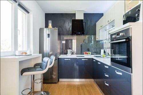 a kitchen with blue cabinets and a bar stool in it at Luxury Apartment with Private Heated Pool in Šibenik
