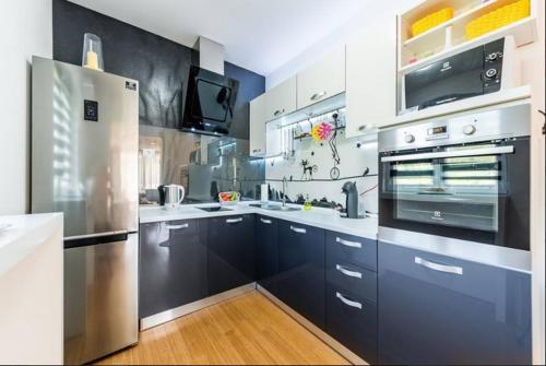 a kitchen with blue cabinets and a stainless steel refrigerator at Luxury Apartment with Private Heated Pool in Šibenik