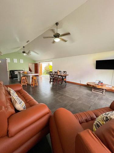 a living room with couches and a flat screen tv at Casa Miel Dulce Escapada en el Paraíso in Puerto Jiménez