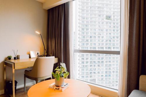 a hotel room with a desk and a large window at The Residences at Novotel Tower in Manila