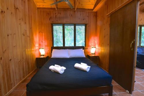 a bedroom with a bed with two towels on it at Daintree Cascades in Cape Tribulation