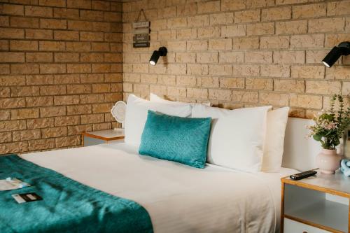 a bedroom with a white bed with a blue pillow at Kennedy Drive Boutique Motel - Close To City Centre & Airport in Tweed Heads