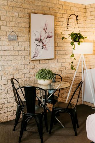 a table with two chairs and a plant on a brick wall at Kennedy Drive Boutique Motel - Close To City Centre & Airport in Tweed Heads