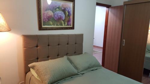 1 dormitorio con 1 cama y una pintura en la pared en Apartamento Cabo Frio Temporada, en Cabo Frío