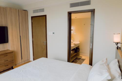 a bedroom with a bed and a bathroom with a sink at The Residences at Novotel Tower in Manila