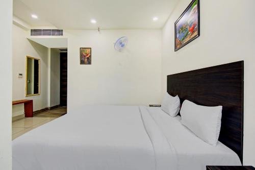 a white bedroom with a large bed and a wall at Hotel O Kinsfolk Inn in Ghaziabad