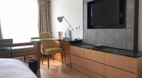 a bedroom with a desk with a television and a bed at Kingtown Hotel Hongqiao Shanghai in Shanghai