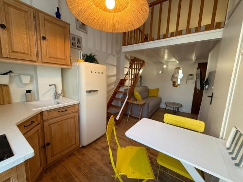 een keuken met gele stoelen en een witte koelkast bij La Plage Studio lumineux, balcon vue mer in Les Sables-dʼOlonne