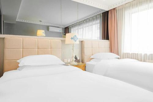 a hotel room with two beds and a window at Hohhot Shanghua Boutique Hotel in Hohhot