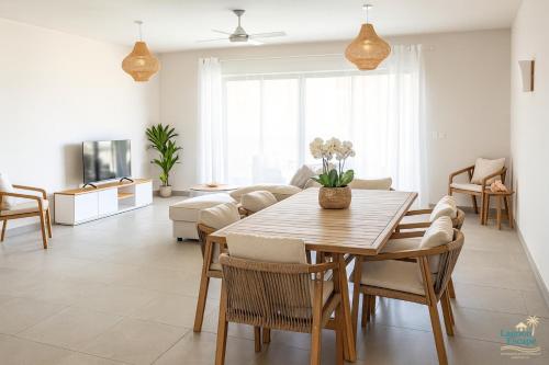 Una sala de estar con una mesa y sillas de madera. en Résidence ORYAM, en Trou aux Biches